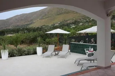 a patio with chairs and a table and umbrella at Villa Cycas Costamante in Castellammare del Golfo