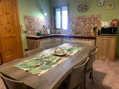 a kitchen with a wooden table with chairs and a counter at Villa Cycas Costamante in Castellammare del Golfo