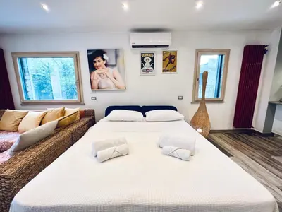 two beds in a room with a couch and a guitar at Casa di Ivana in Carini