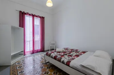a bedroom with a bed and two large windows at GuestHost - Palermo Central Apartment in Palermo