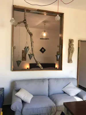a living room with a blue couch and a mirror at Casetta dei Legni in Palermo