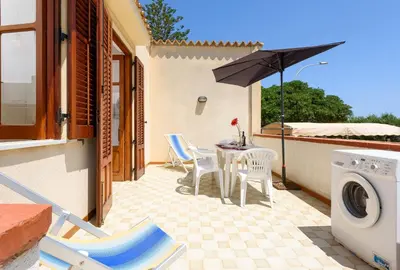 a patio with a table and chairs and an umbrella at Casa Vacanza Azzurra 3 in San Vito lo Capo