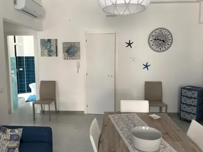a living room with a table and chairs and a clock at Casa Rosita in San Vito lo Capo