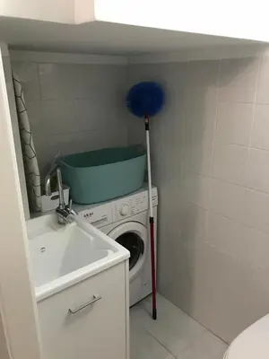 a washer and dryer with a blue broom in a bathroom at Casa Rosita in San Vito lo Capo