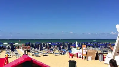 a beach with chairs and umbrellas and the ocean at Il Sole di Sicilia in Castellammare del Golfo