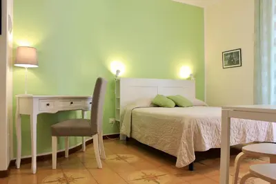 a bedroom with a bed and a desk and a chair at Gli Artisti Apartments & Rooms in Bagheria