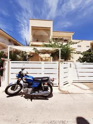a motorcycle parked in front of a white fence at Castellammare Holiday in Alcamo Marina