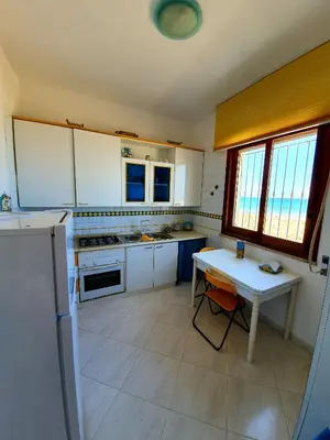 a kitchen with white cabinets and a table in it at Castellammare Holiday in Alcamo Marina