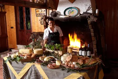 a woman standing in front of a table with a fireplace at Agriturismo Al Poggetto in Piana degli Albanesi