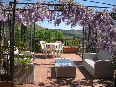 a patio with a table and chairs and purple flowers at Agriturismo Al Poggetto in Piana degli Albanesi