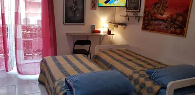 two beds in a room with a table and a window at Casa Albergheria in Palermo