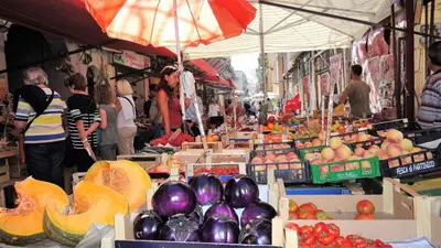 a market with fruits and vegetables and people standing around at Casa Albergheria in Palermo