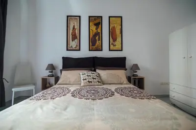 a bedroom with a large bed with four pictures on the wall at Via Vittorio Emanuele Apartment in Palermo