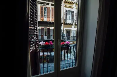 a window with a view of a balcony with flowers at Via Vittorio Emanuele Apartment in Palermo