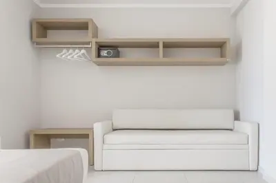 a white couch sitting in a room next to a bed at Residence Le Piscine in San Vito lo Capo