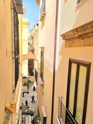 an alley between two buildings with people walking down it at Natoli Apartments in Palermo
