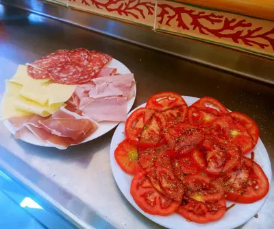 two plates of meat cheese and tomatoes on a counter at B&B Donna Sabella in Santa Flavia
