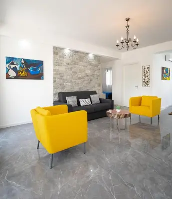 a living room with a couch and two yellow chairs at Arricàmpati Apartments Villa & Bringo Car Rental in Carini