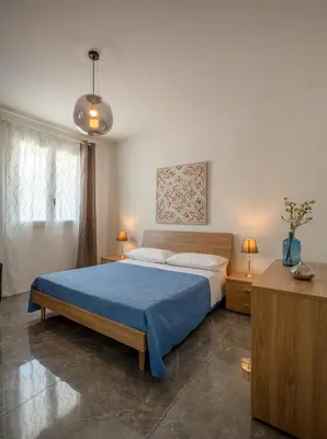 a bedroom with a large bed with a blue blanket at Arricàmpati Apartments Villa & Bringo Car Rental in Carini
