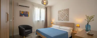 a bedroom with a bed and a chair and a window at Arricàmpati Apartments Villa & Bringo Car Rental in Carini