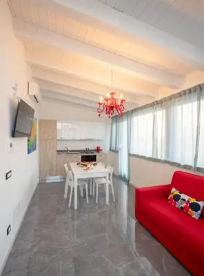 a living room with a red couch and a table at Arricàmpati Apartments Villa & Bringo Car Rental in Carini