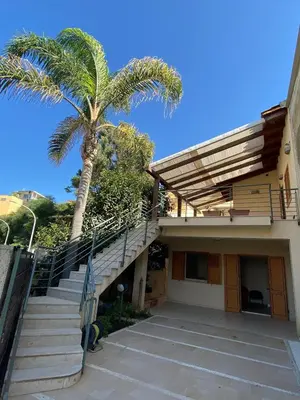 a palm tree sitting next to a building with stairs at Appartamento casa mare in Alcamo Marina