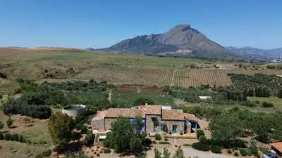 a house in a field with a mountain in the background at Terre Di Himera in Buonfornello