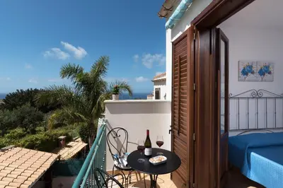 a small balcony with a table and two glasses of wine at Appartamenti Irene in Macari
