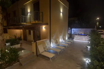 a row of white chairs in a courtyard at night at B&B Aloe Comfort Rooms in San Vito lo Capo
