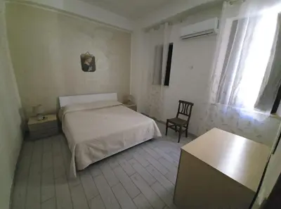 a bedroom with a white bed and a chair at casa francesca in Castellammare del Golfo