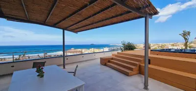 a balcony with a table and benches and the ocean at Saracen Sands Hotel & Congress Centre - Palermo in Isola delle Femmine