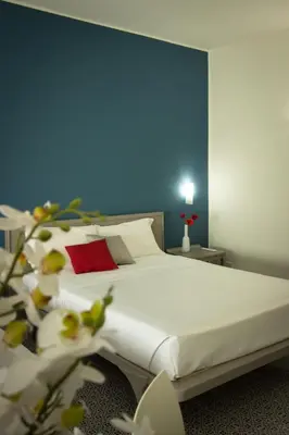 a bedroom with a white bed with a blue wall at Saracen Sands Hotel & Congress Centre - Palermo in Isola delle Femmine