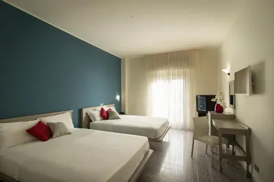 a hotel room with two beds and a desk at Saracen Sands Hotel & Congress Centre - Palermo in Isola delle Femmine