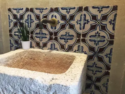 a bathroom with a stone tub with a tile wall at Kurò in Palermo