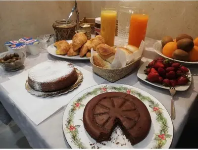 a table topped with plates of food and cakes and fruit at Kurò in Palermo