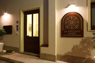 a sign on the side of a building with a door at La Nicchia Smart in San Vito lo Capo