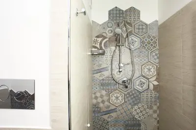 a shower in a bathroom with a mosaic wall at La Nicchia Smart in San Vito lo Capo