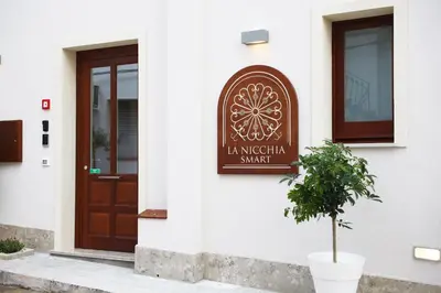 a sign on the side of a building with a door at La Nicchia Smart in San Vito lo Capo