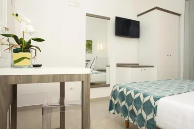 a room with a bed and a desk with a table at La Nicchia Smart in San Vito lo Capo