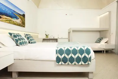 a white bedroom with a bed and a couch at La Nicchia Smart in San Vito lo Capo