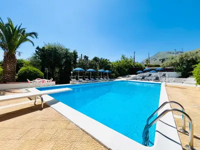 a large swimming pool with chairs and umbrellas at Villa Giada in Carini