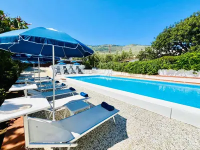 a pool with a bunch of chairs and an umbrella at Villa Giada in Carini