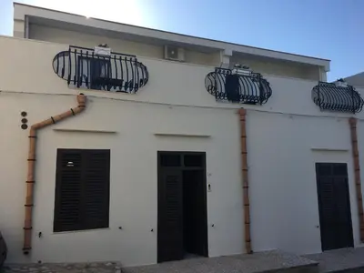 a white building with two balconies on top of it at Scopelos in Scopello