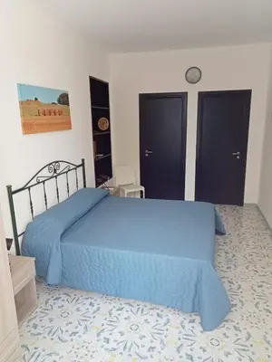 a bedroom with a blue bed and two black doors at Scopelos in Scopello