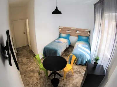 a small bedroom with two beds and a table and chairs at Be Central Rooms in Palermo
