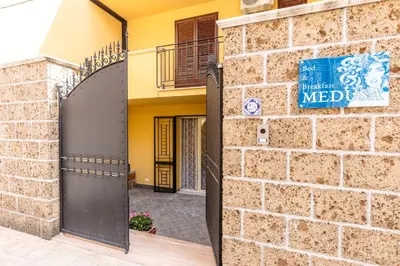 a brick wall with a gate to a building at B&B Medusa in Santa Flavia