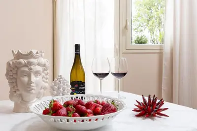 a table with a bowl of strawberries and a bottle of wine at B&B Medusa in Santa Flavia