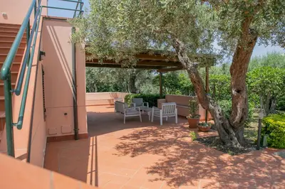 a patio with a tree and a table and chairs at Villa Bruna in Cefalù