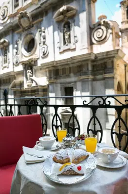 a table with a plate of food and orange juice at B&B Santa Caterina in Palermo