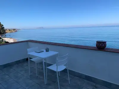 a table and chairs on a balcony overlooking the ocean at Sfondo Blu Villa sul mare in Trabia